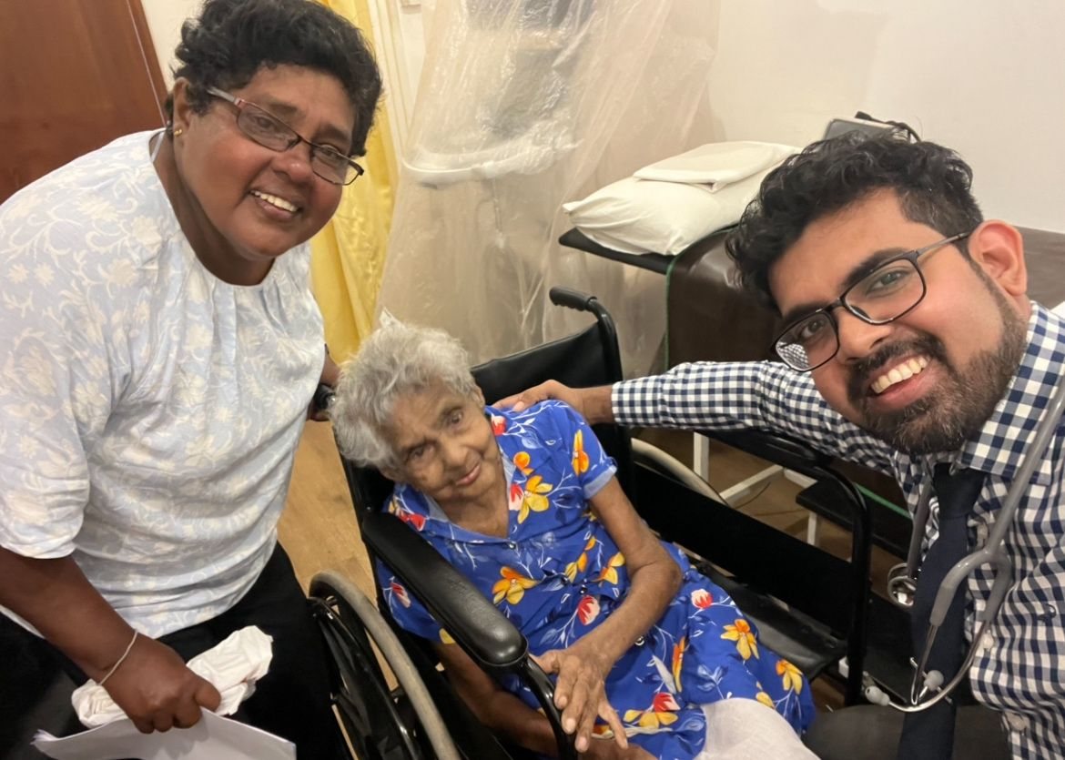 Dr Sithira Senevirathne with one of his patients, seated in a wheelchair, and her carer in a Colombo clinic room