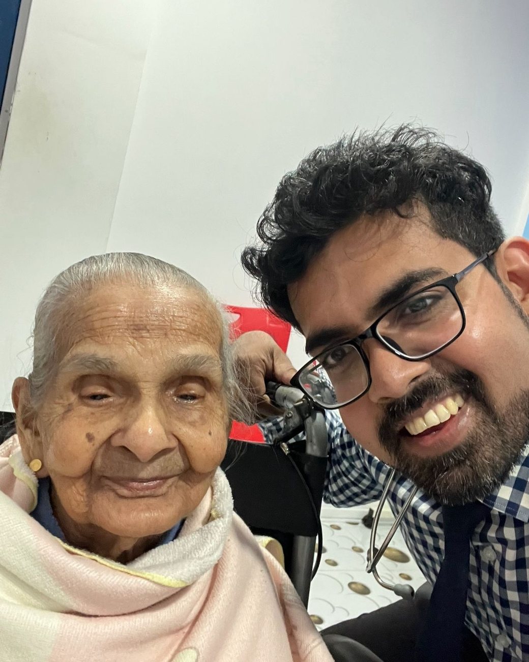Dr Sithira Senevirathne beside an elderly patient wrapped in a pink shawl during a clinic visit